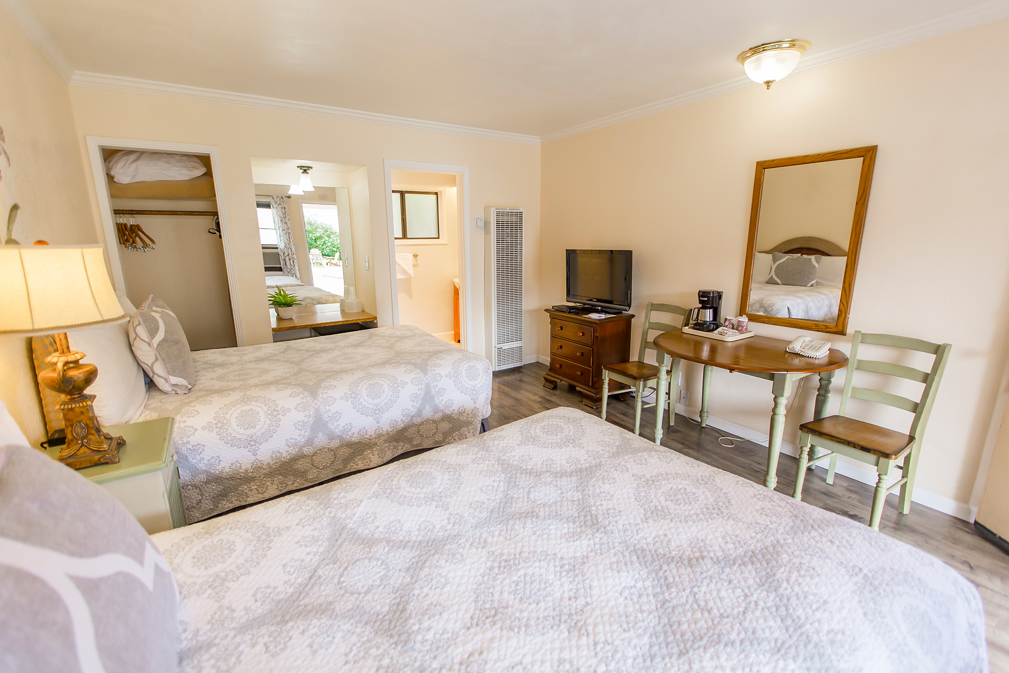 A hotel room with two beds, a desk, and a TV.