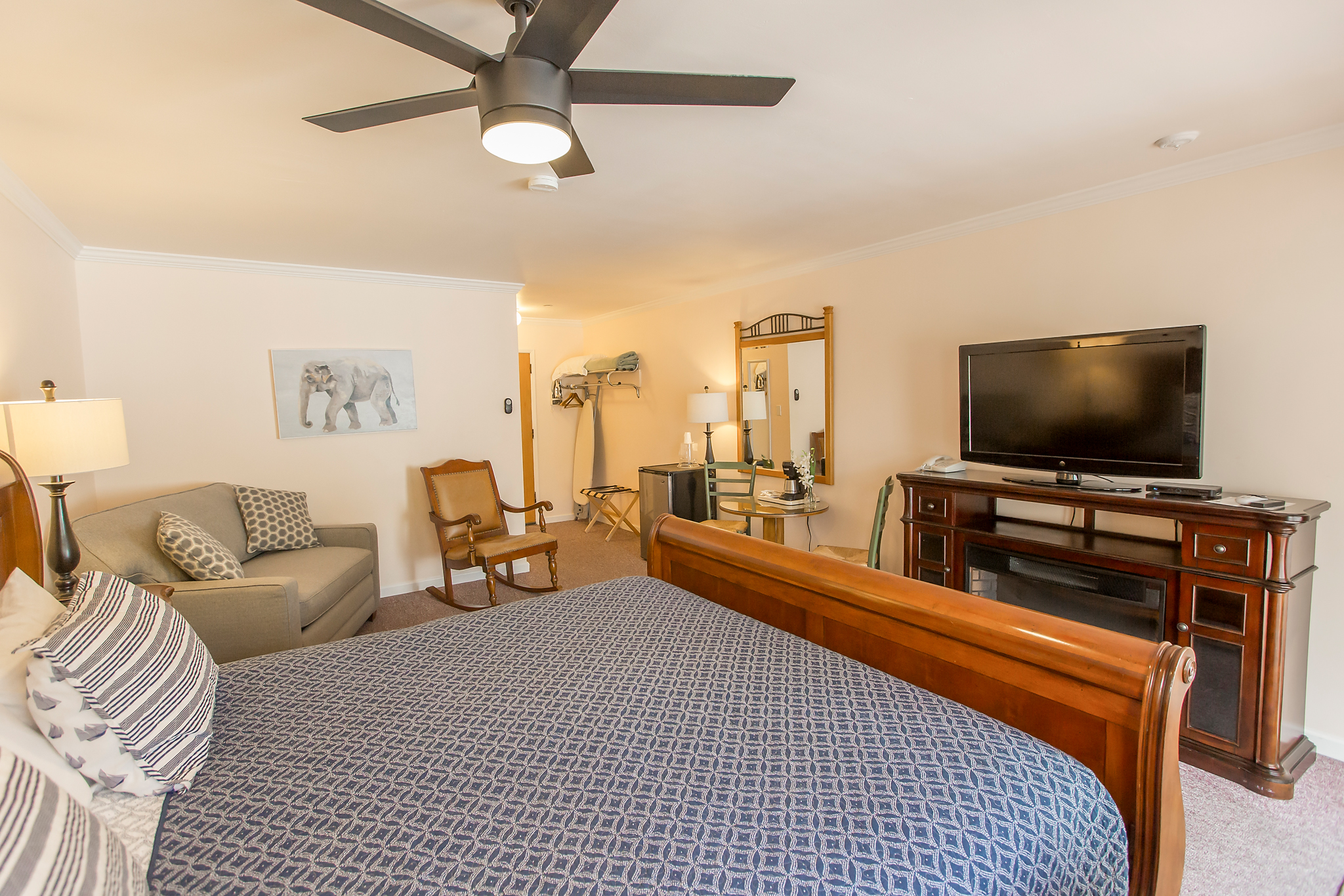 A wide view of a hotel room with a large bed, a sitting area, and a TV on a wooden dresser.